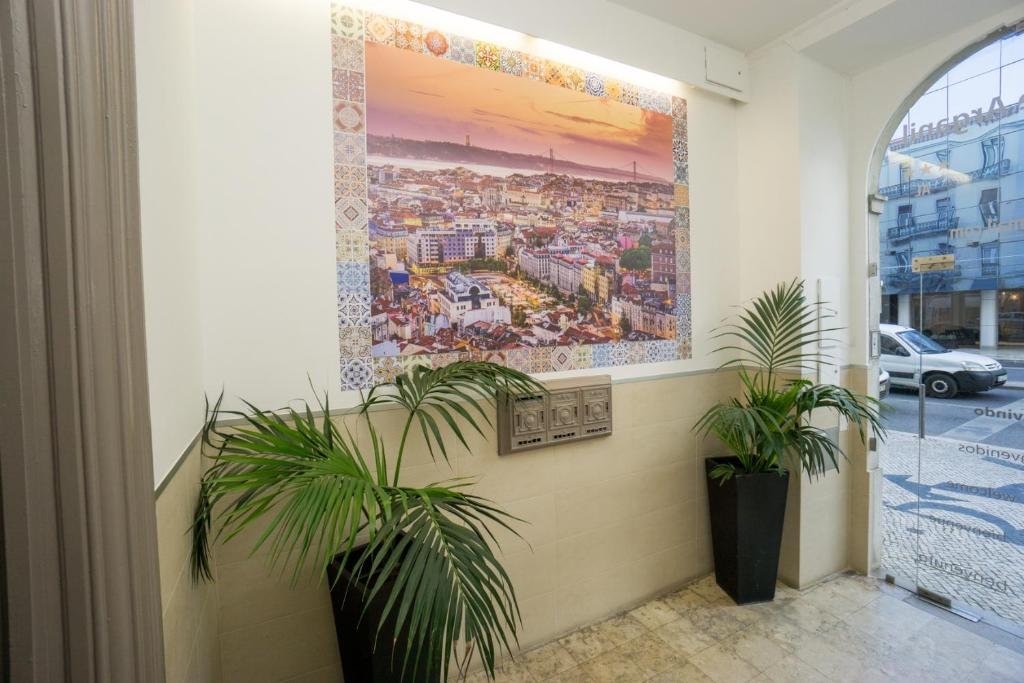 Hall de entrada acolhedor do Hotel Estrela de Arganil com mural de Lisboa e plantas tropicais